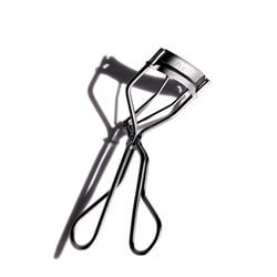 "The award-winning Shiseido Eyelash Curler, featuring the Shiseido logo, crimps and curls eyelashes. The makeup tool has a curved shape with two handles that meet at a hinge in the middle. "